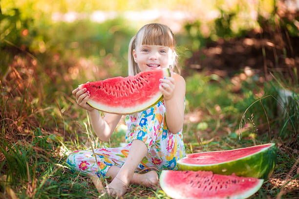istock Little girl with watermelon sitting 607477922