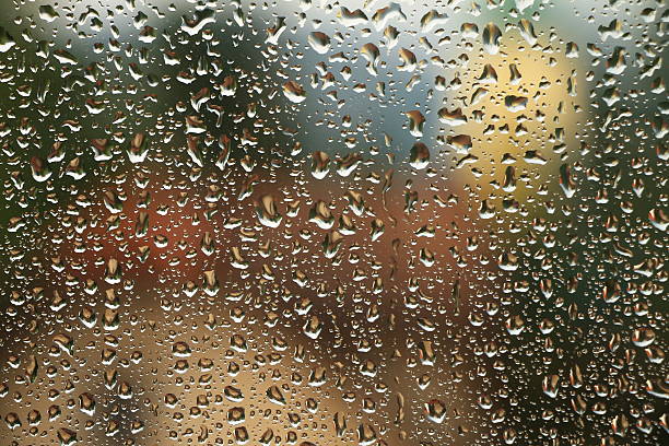 istock Rain drops on window with house and church in background 607478982