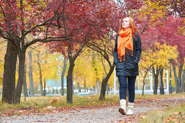 istock girl walk on pathway in city park with red trees 607481504