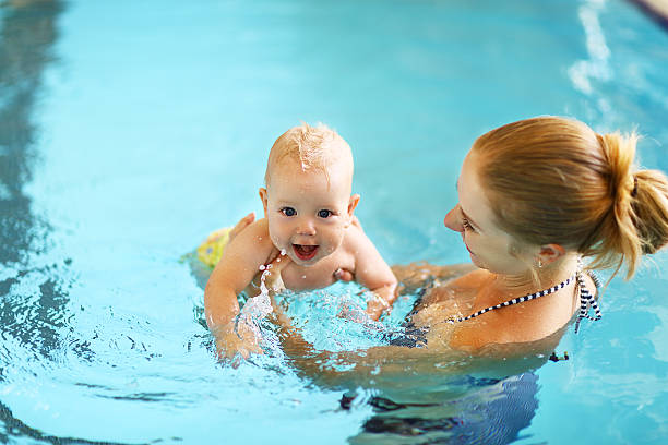 istock mother teaching baby swimming pool 607482418