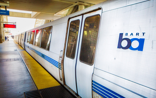 San Jose, USA - May 10, 2016: San Francisco bart train at San Jose station on a sunny day. A few people are waiting in the background.