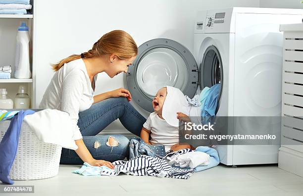 Mother A Housewife With A Baby Fold Clothes Stock Photo - Download Image Now - Mother, Cleaning, Baby - Human Age