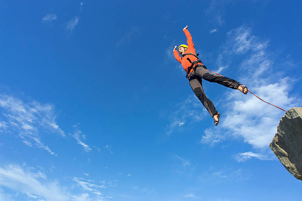 Jump rope from a high rock in the mountains. The first jump off the cliff with a safety rope. bungee jumping stock pictures, royalty-free photos & images