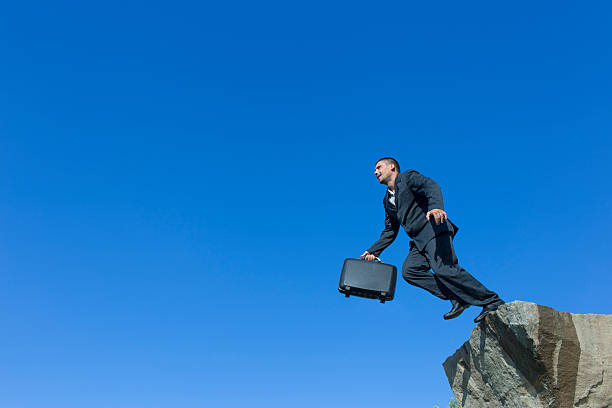 istock Jumping man with a diplomat from a cliff. 607485156