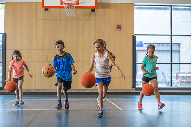 Dribbling Basketballs Up the Court A multi-ethnic group of elementary age children are dribbling basketballs down the court in the gym. bouncing stock pictures, royalty-free photos & images