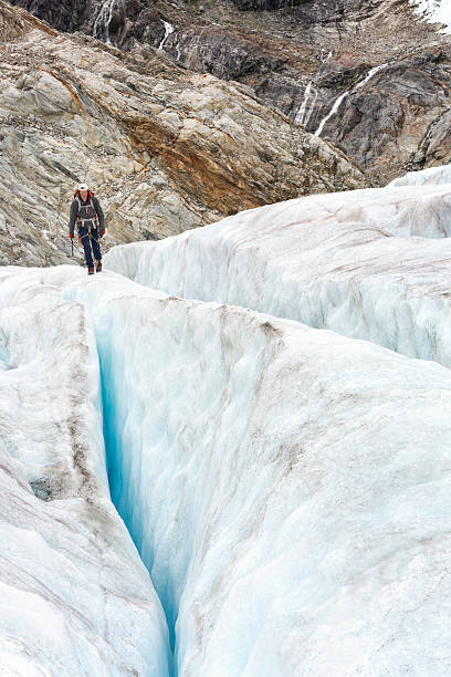 istock Man hikes across dangerous ridge between crevasses 607486882