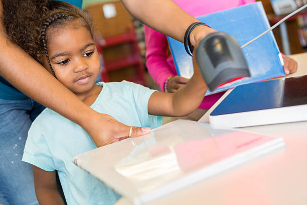istock Cute African American toddler scanning a library book 607487316
