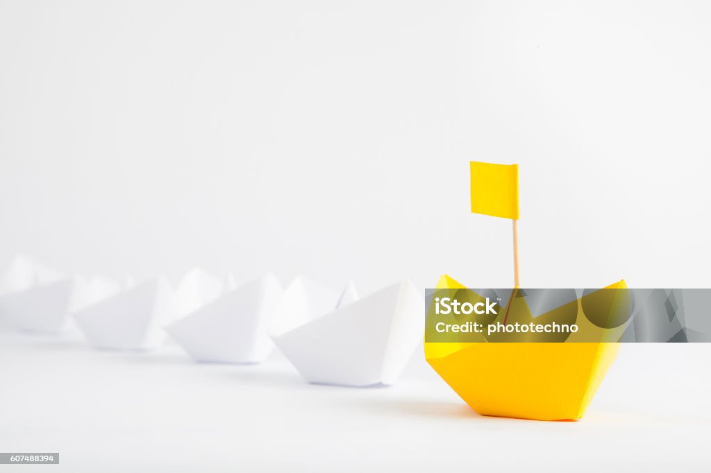 Führungskonzept mit gelbem Papierschiff führt unter weißen Schiffen - Lizenzfrei Führungstalent Stock-Foto