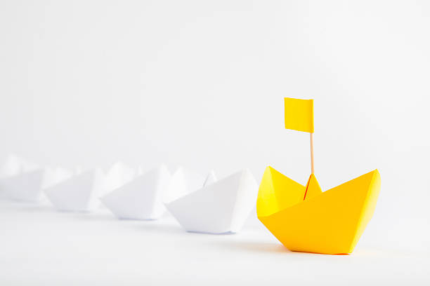 istock Leadership concept with yellow paper ship leading among white ships 607488394