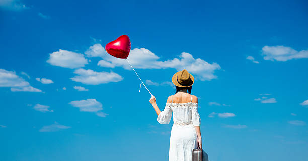 istock young woman with suitcase and balloon 607488544