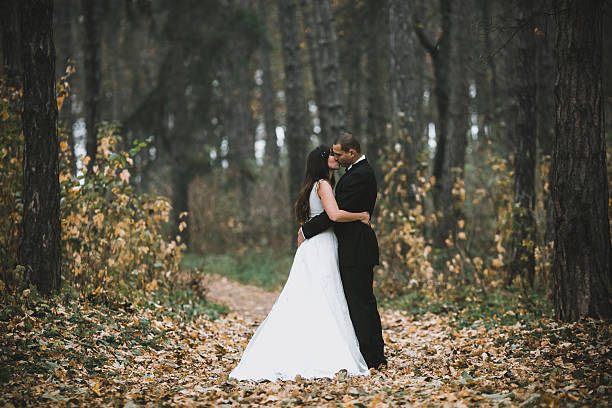 istock happy bride and groom posing in the autumn forest 607492242
