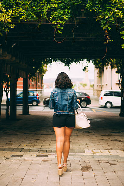 istock Young woman walking with purse 607493432
