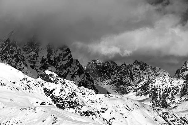 istock Black and white snowy rocks in clouds at sunny day 607493460