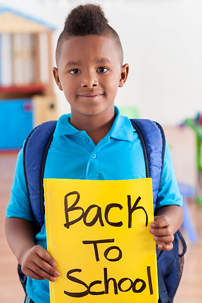 istock Boy holds 'Back to School' sign at school 607493656