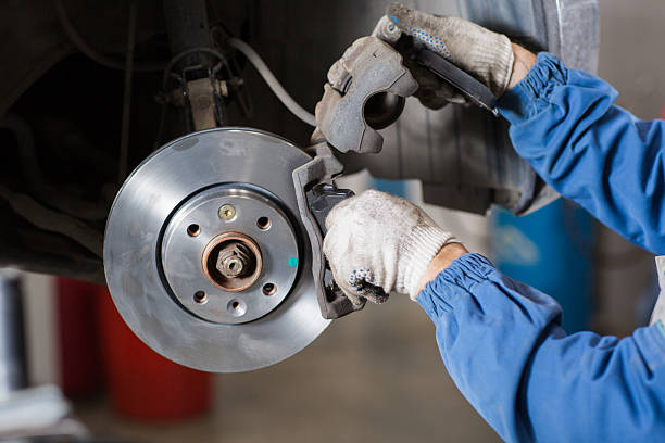 istock Brand new brake disc on car in a garage. Auto 607495318