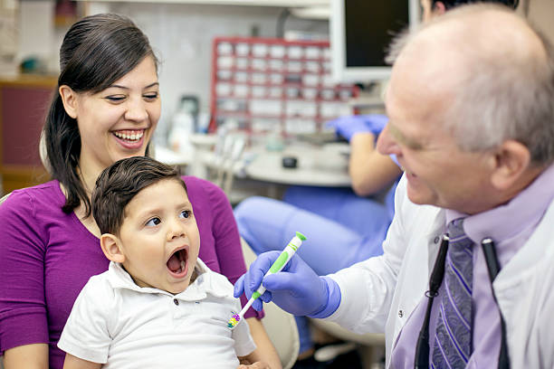 istock Ethnic mother holds son as he gets his teeth cleaned 607496980