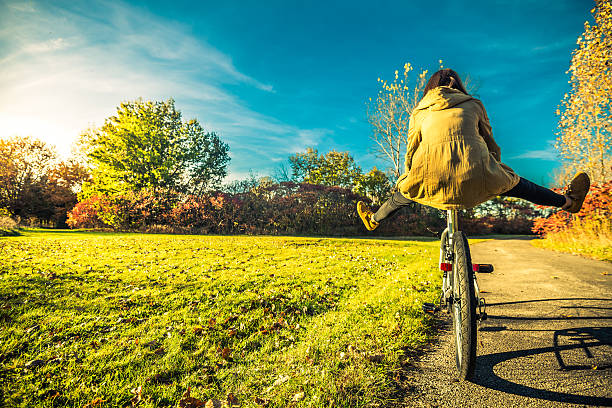 jeune femme s’amusant sur le vélo dans le parc - être aux anges photos et images de collection