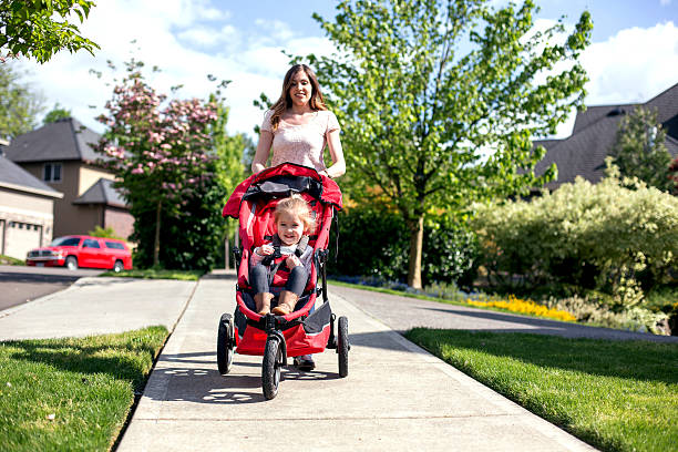 istock Young mother pushes her daughter in a stroller 607498034