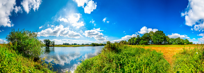 Summer landscape with river, blue sky, trees and sun