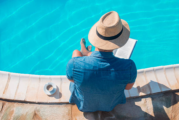 istock man reading a book on the swimming pool 607500988