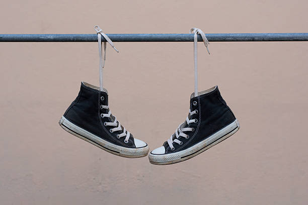 istock Black sneakers hanging on metal bar 607501204