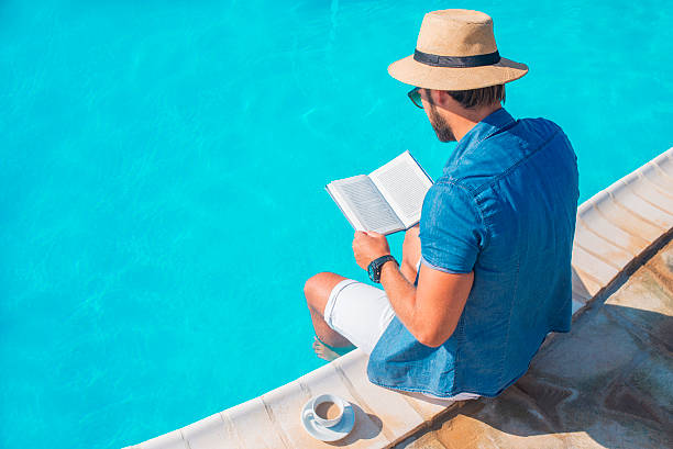 istock man reading a book by the swimming pool 607502288
