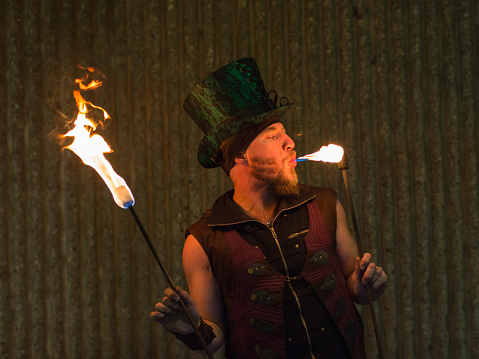 Mid adult fire juggler woman performing using flaming torch at night outdoors