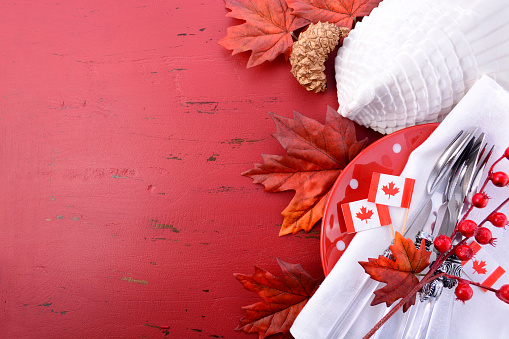 Canada red and white theme Thanksgiving background with decorated borders on a distressed red wood table, with a white turkey tureen and Canadian Maple Leaf Flag.