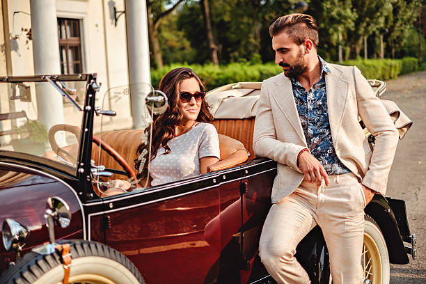 man hitting on a woman in a classic convertible - retro revival couple men elegance imagens e fotografias de stock