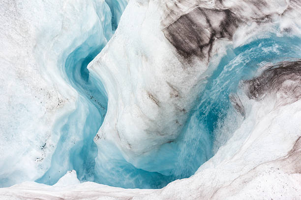 Rushing water tunnels through the ice descending into a moulin on Lemon Glacier, Juneau Icefield, Juneau, Alaska, USA