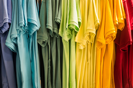 Hanging t shirts arranged in rainbow colors.