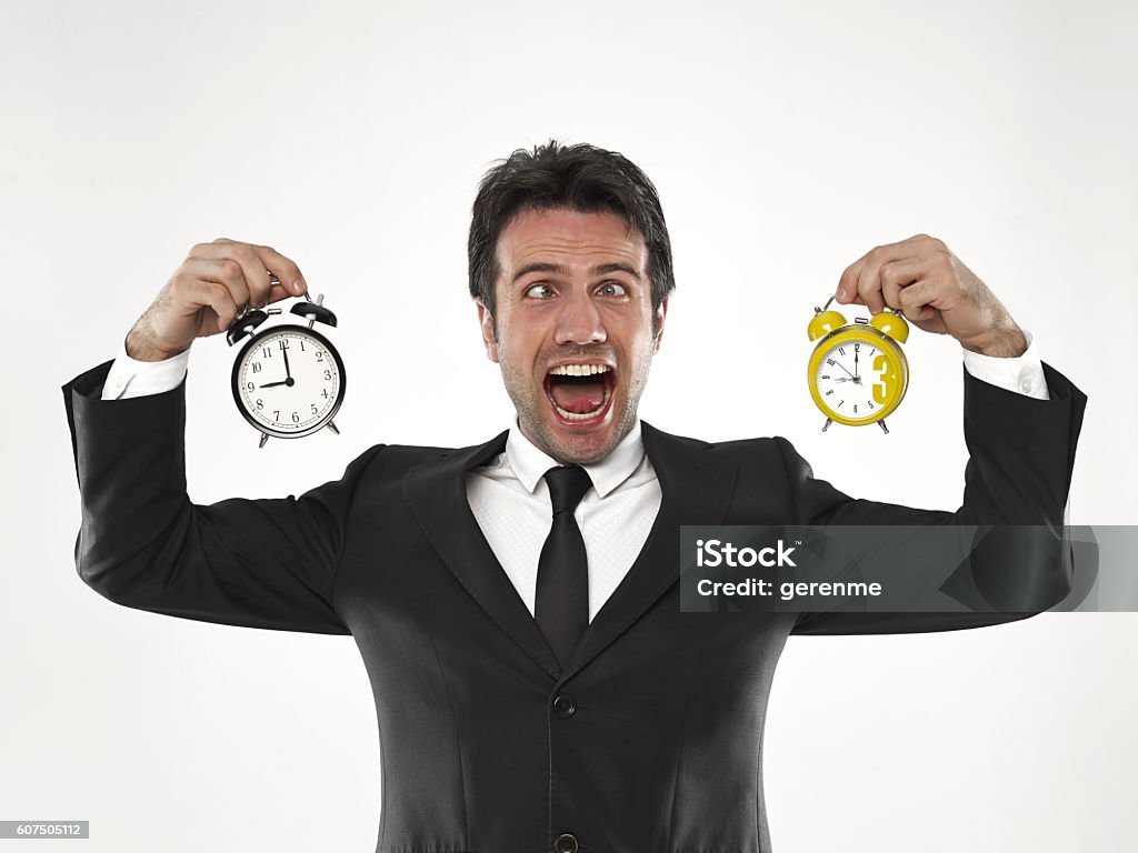 Businessman holding clock Businessman holding  holding clock in front of his face Bizarre Stock Photo