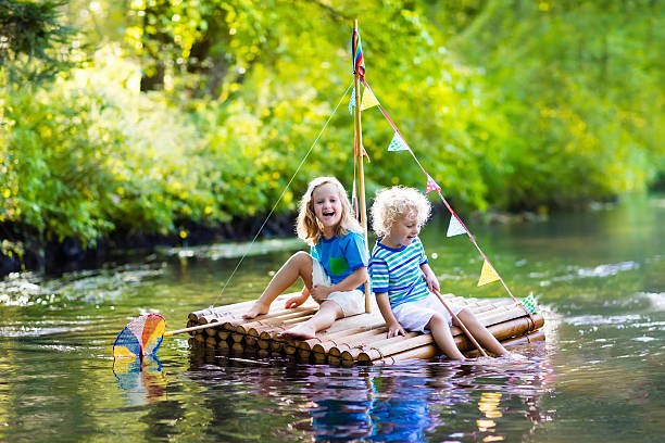 木製のいかだに乗った2人の小さな子供たち - wooden raft ストックフォトと画像