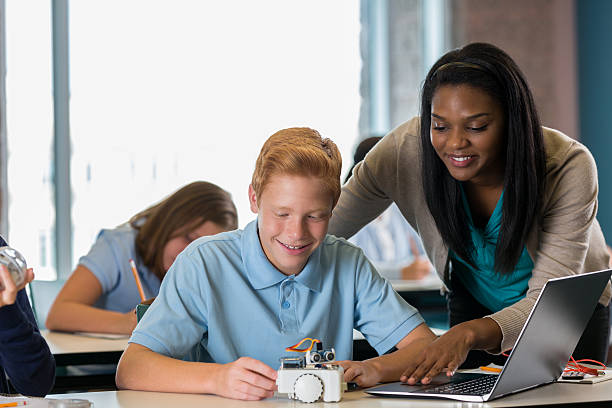 istock Teacher assisting teenage boy with robotics assignment in STEM class 607588740