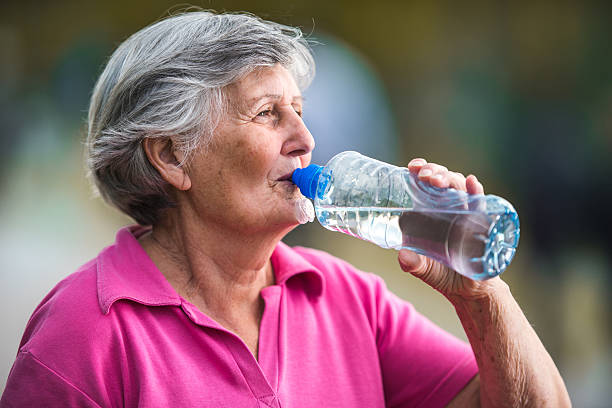 Senior woman drinking refreshing water from a bottle.