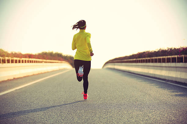 istock young woman runner running on city bridge road 607598078