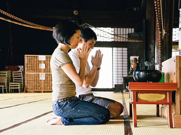 istock Japanese couple praying in a buddhist temple 607602086