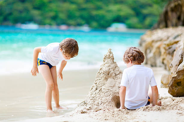 istock Two kid boys building sand castle on tropical beach 607602182