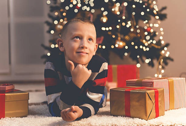 istock Cute little boy with present on Christmas eve thinking 607602656