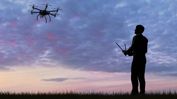istock man operating of flying drone multicopter UAV at sunset 607603446
