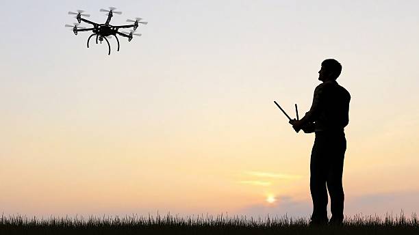 istock man operating of flying drone multicopter UAV at sunset 607603502