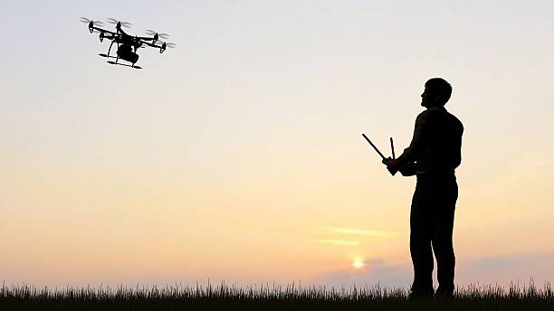 istock man operating of flying drone multicopter UAV at sunset 607603540