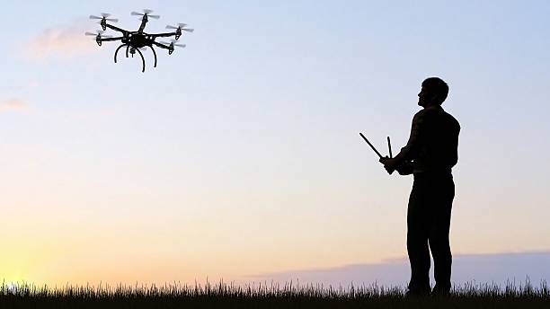 istock man operating of flying drone multicopter UAV at sunset 607603748