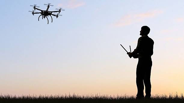 istock man operating of flying drone multicopter UAV at sunset 607603802