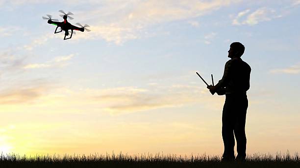 istock man operating of flying drone quadrocopter UAV at sunset 607603978