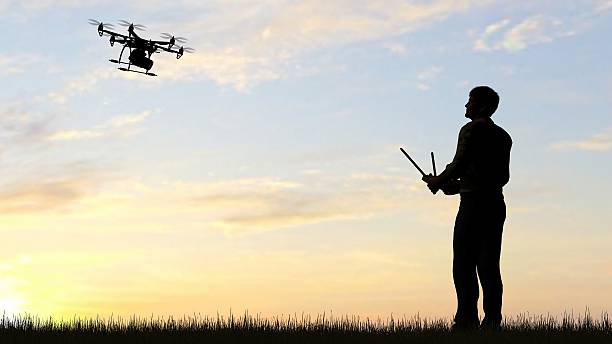 istock man operating of flying drone multicopter UAV at sunset 607604040