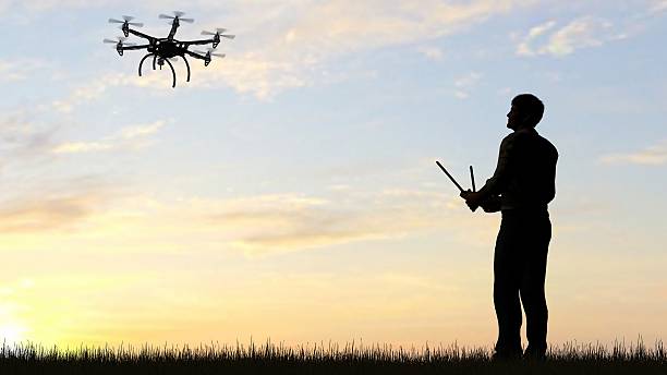istock man operating of flying drone multicopter UAV at sunset 607604088