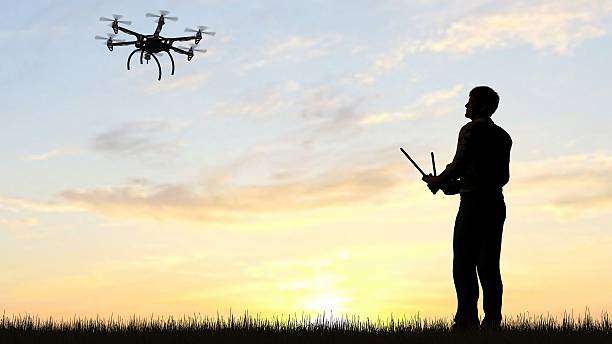 istock man operating of flying drone multicopter UAV at sunset 607604142
