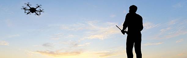 istock man operating of flying drone multicopter UAV at sunset panorama 607605074