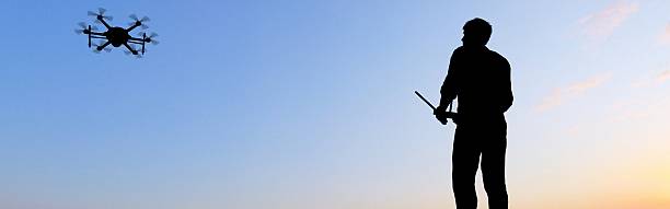 istock man operating of flying drone multicopter UAV at sunset panorama 607605128